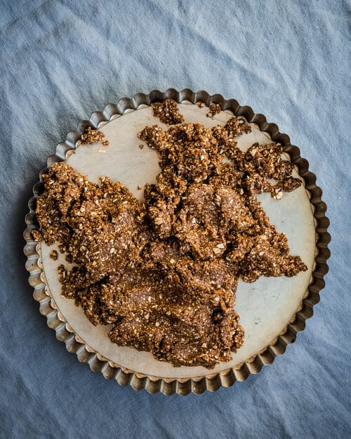 Crust added to tart pan before being pressed down.