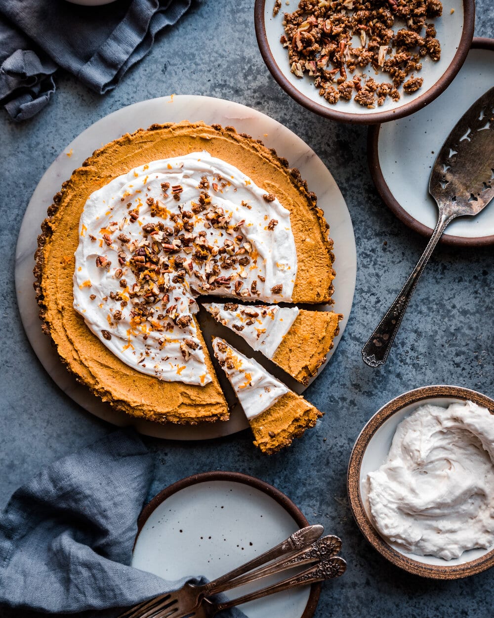 Sliced pumpkin cream tart on a marble platter on grey table.