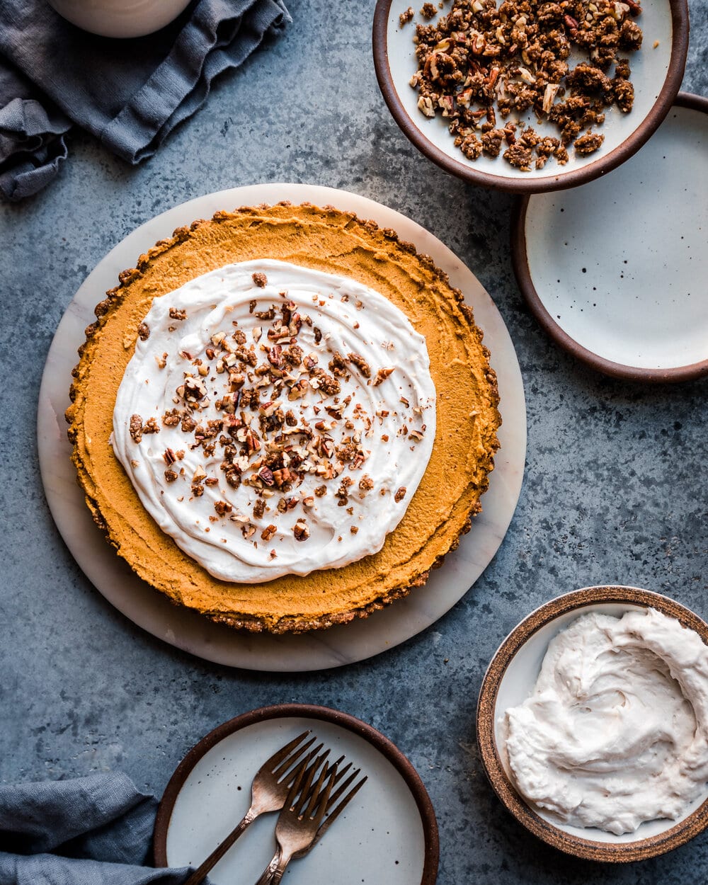 Full pumpkin tart on marble serving board on grey table. 