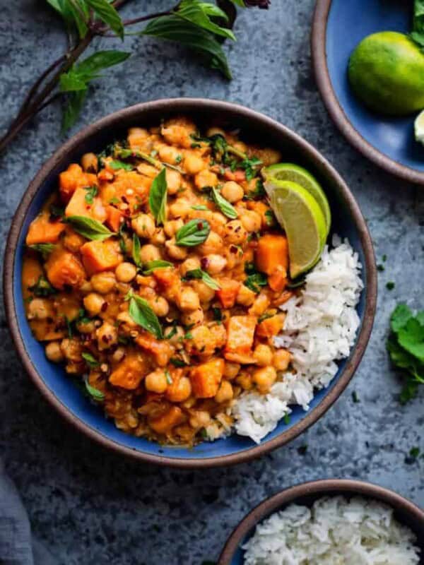 butternut squash curry with chickpeas in a blue ceramic bowl with white rice and lime wedges.