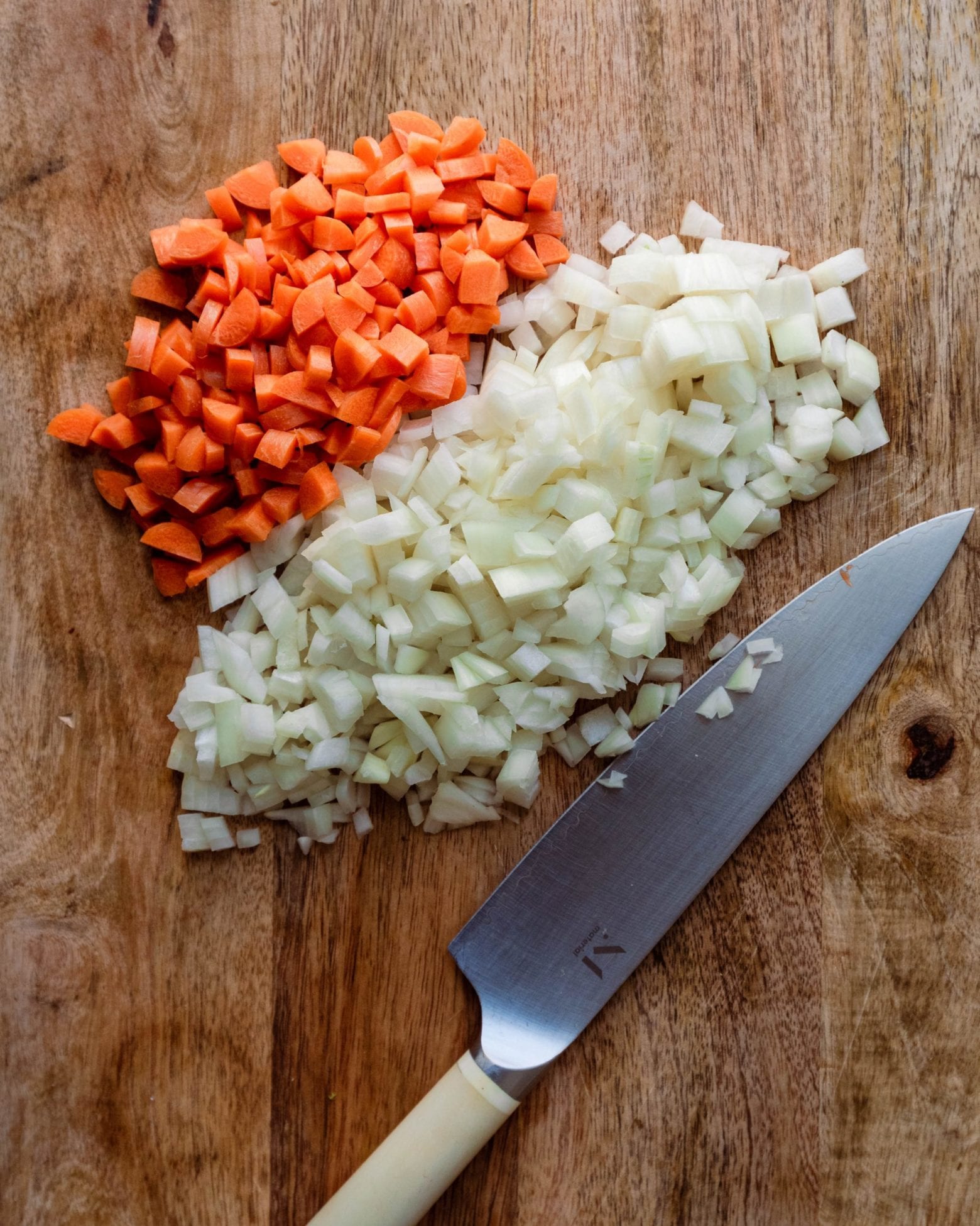 diced carrots and onions on wooden cutting board