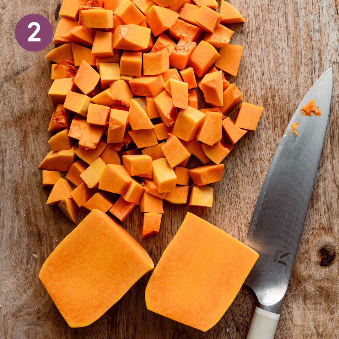 diced butternut squash on a cutting board with a knife. 