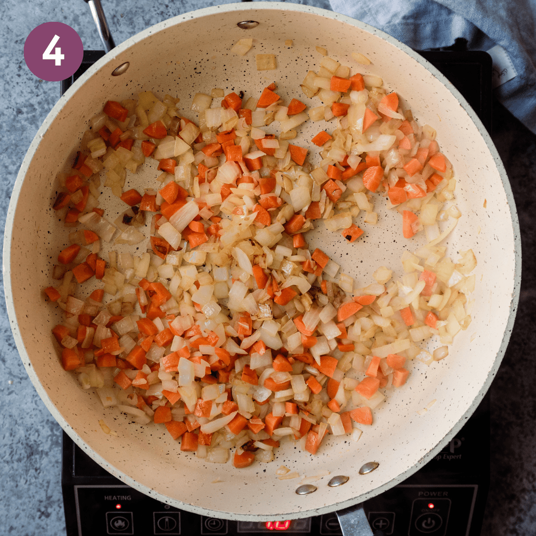 onions and carrots sauteeing in a pan.