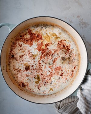 coconut milk and other ingredients being poured into dutch oven