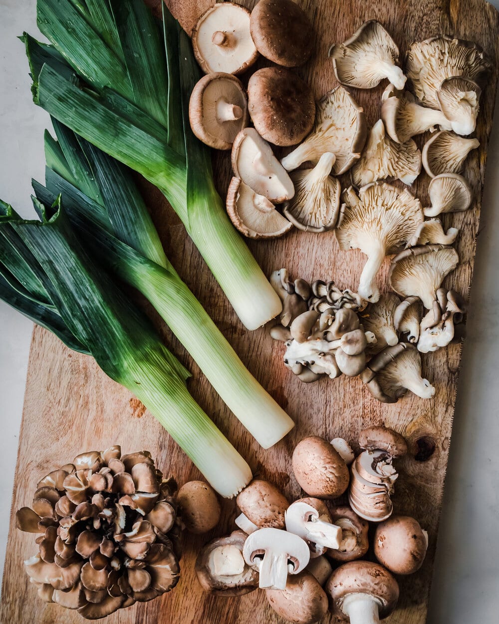 mushrooms and leeks on wooden cutting board