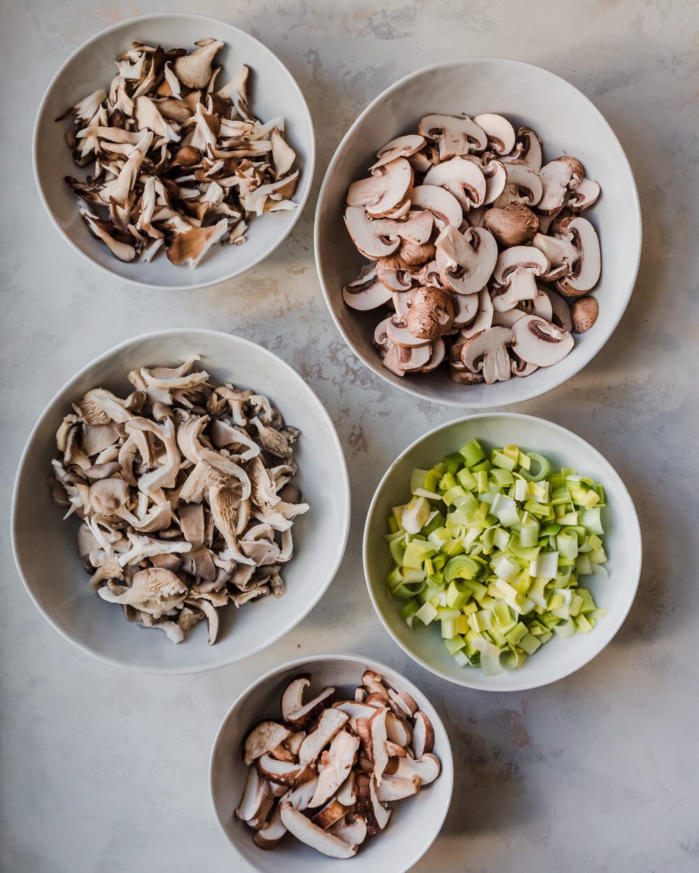 bowls containing mushrooms and leeks arranged on a table