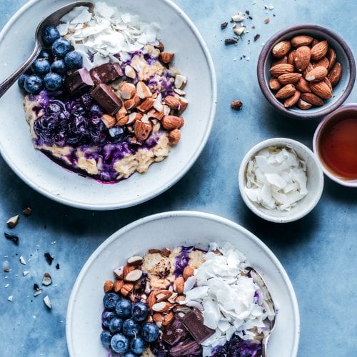 bowls of oatmeal with stewed blueberries, almonds, and coconut