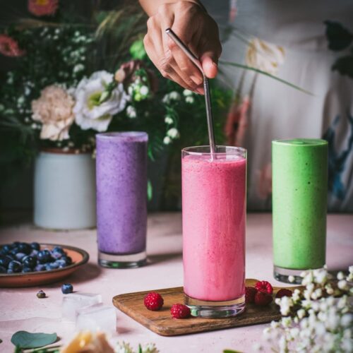 Woman stirring straw in raspberry tahini smoothie.