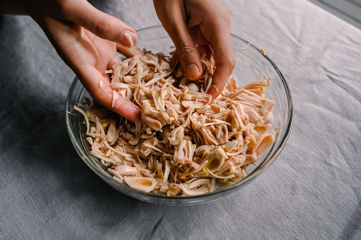 woman's hands shredding jackfruit in a bowl