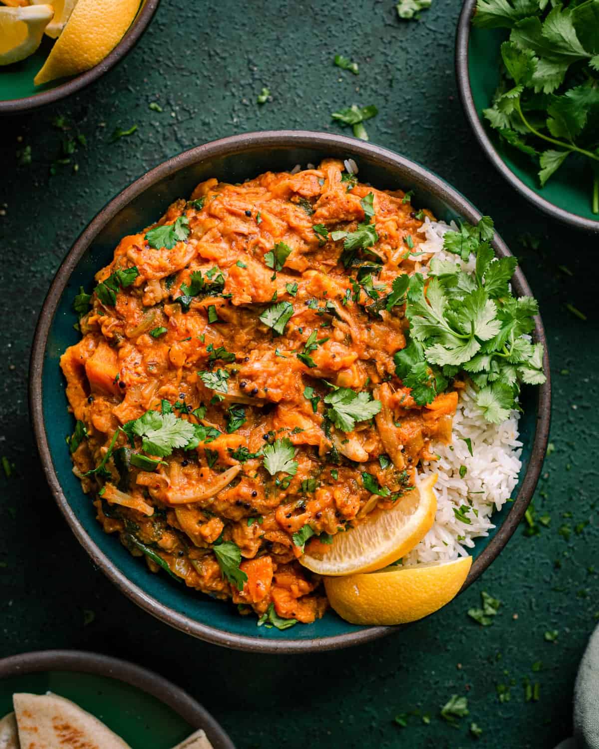 vegan jackfruit curry in green bowl with rice and cilantro on green photography backdrop