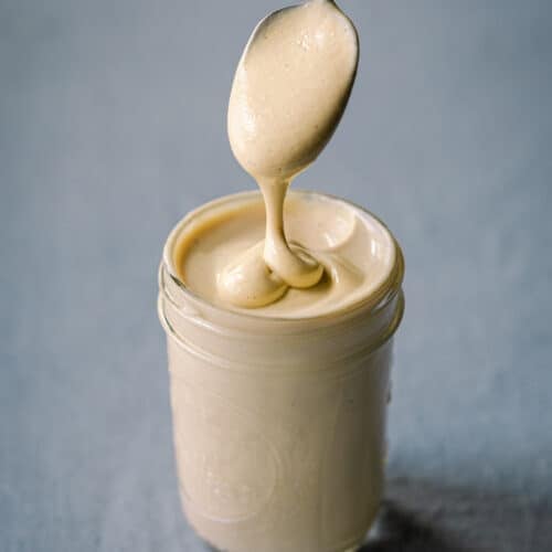 spooning cashew cream in glass jar