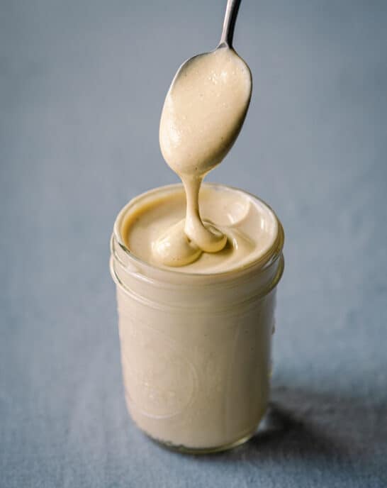 spooning cashew cream in glass jar