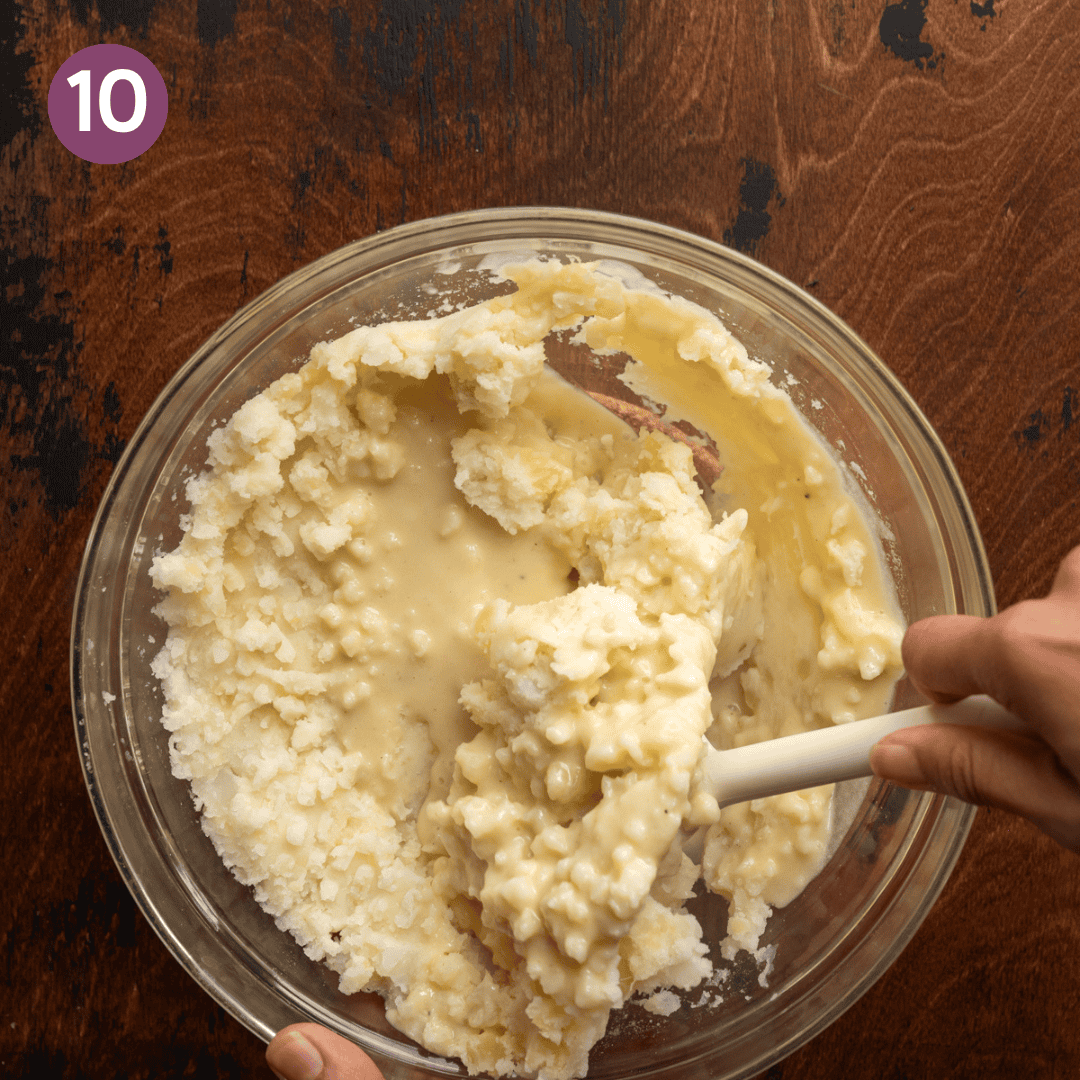 silicone spatula folding melted butter-milk mixture into mashed potatoes.