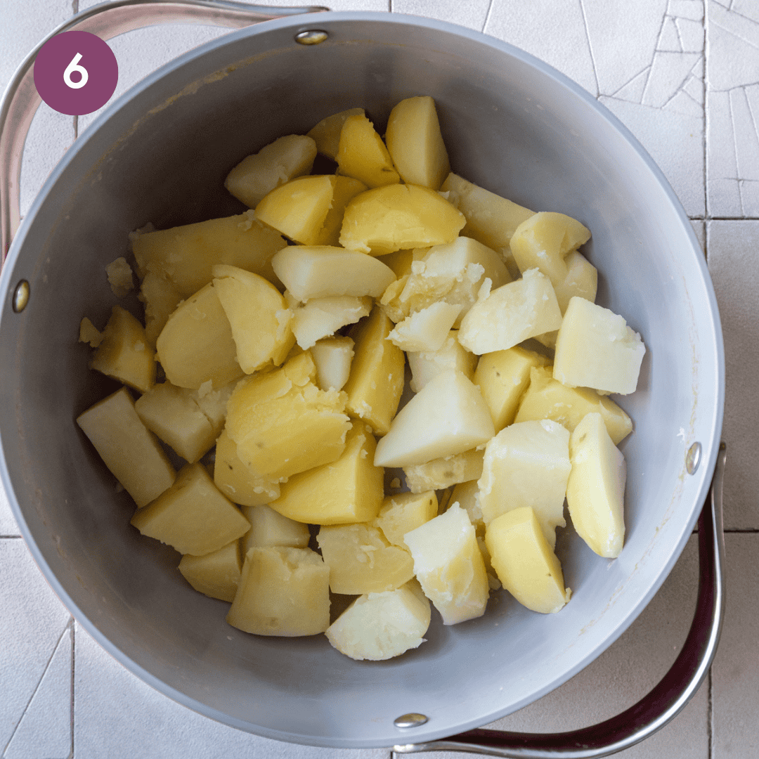 peeled, chopped potatoes that have been cooked, sitting in a saucepan.