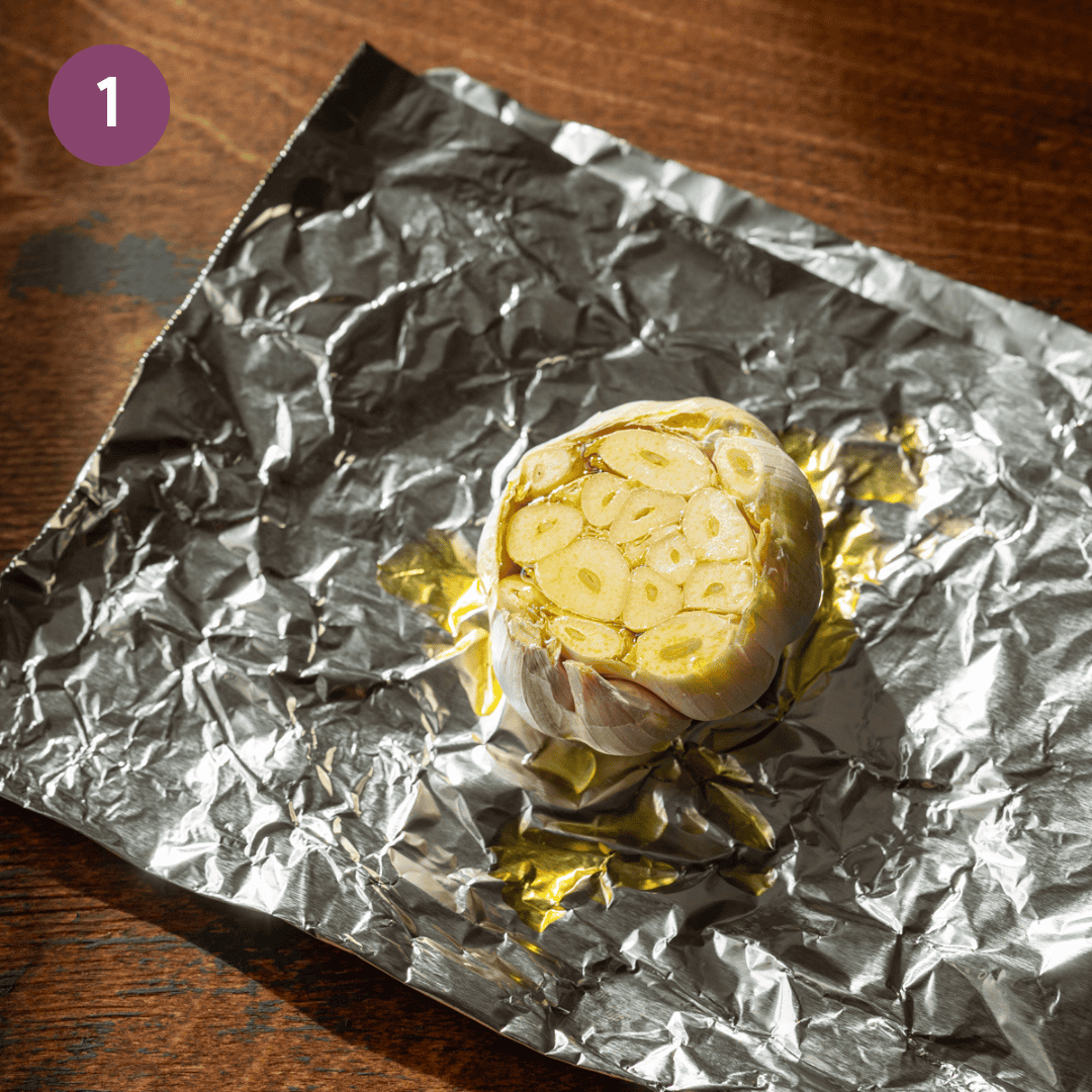 head of garlic with top sliced off, drizzled with oil, on a piece of foil. 