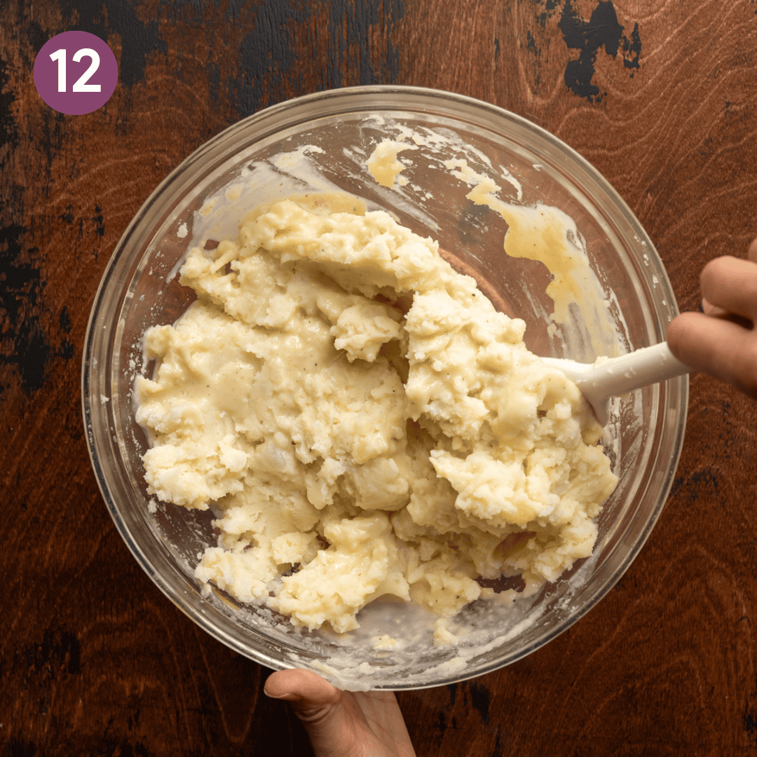 silicone spatula folding melted butter-milk mixture into mashed potatoes.