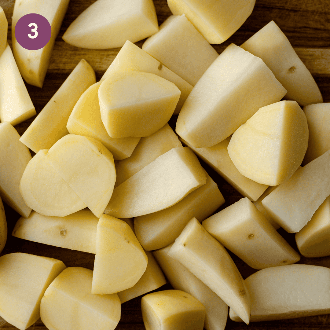 peeled and chopped potatoes on a wooden cutting board.