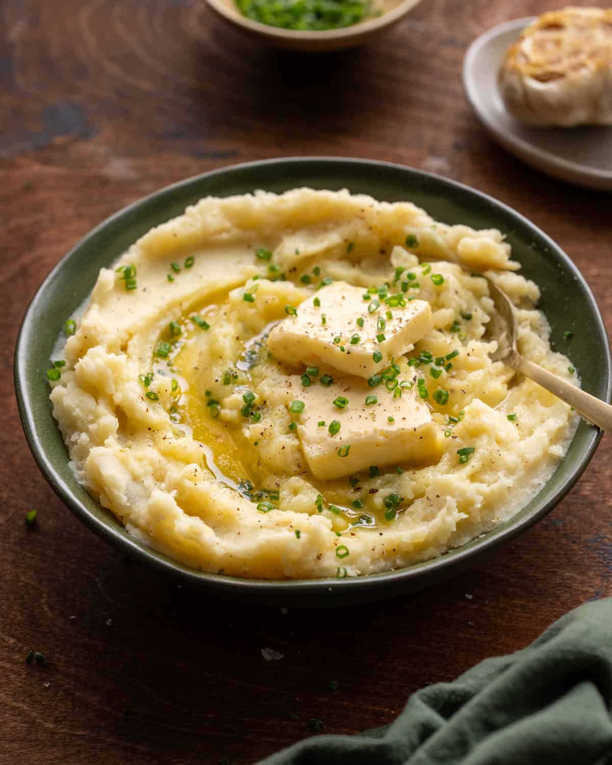 backlit shot of mashed potatoes in a bowl with butter on a wooden table.