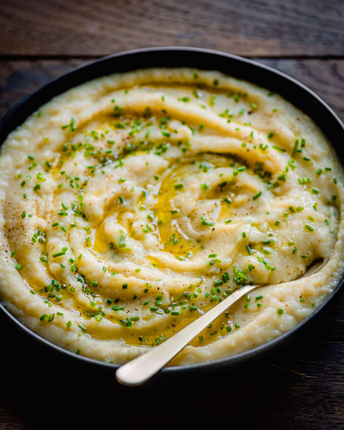 backlit photo of vegan mashed potatoes with chives on a wooden table