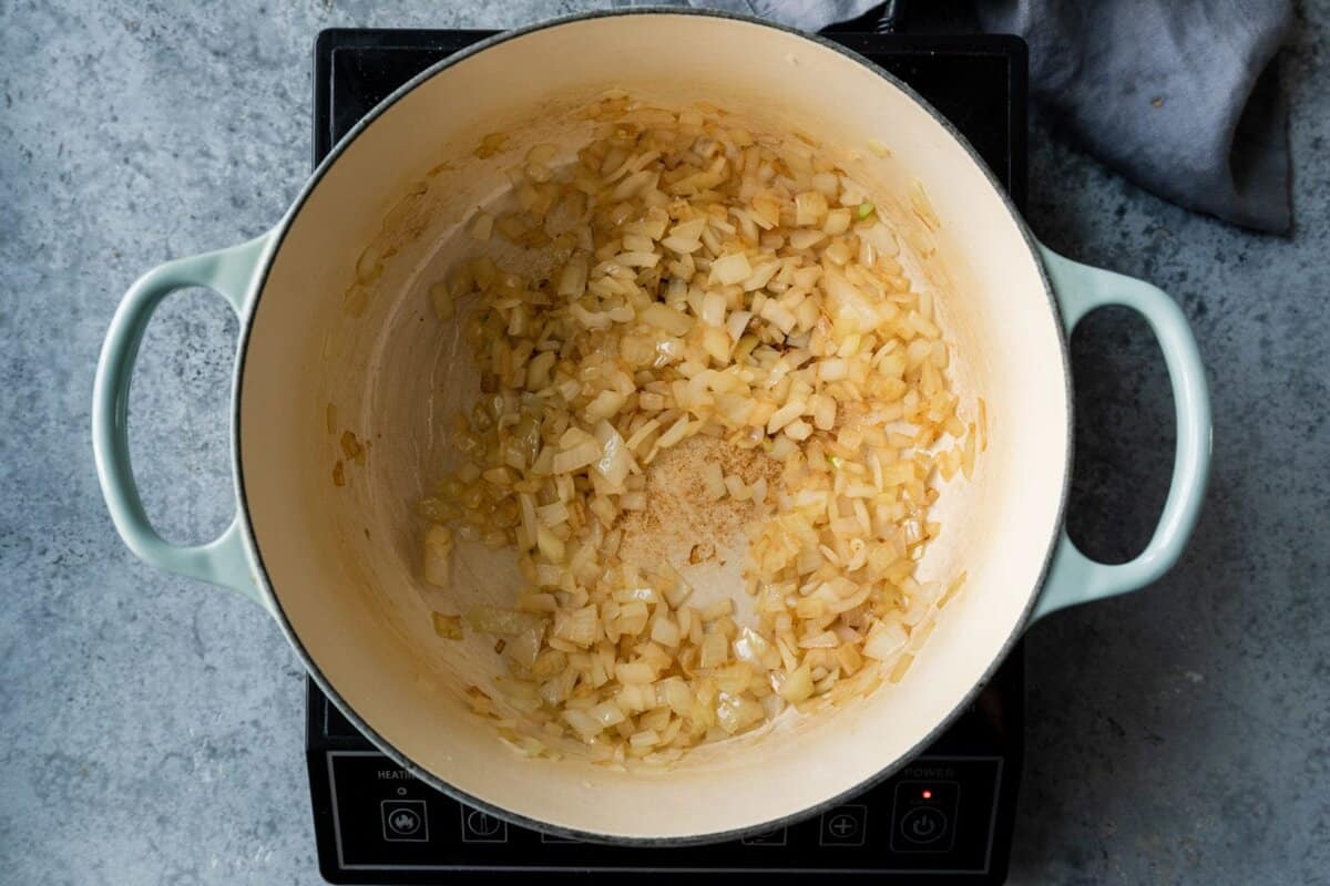 onions being sauteed in a Dutch oven.