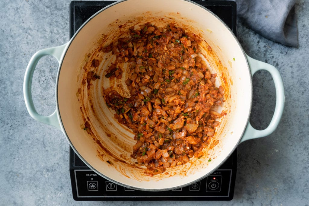 cooked onions, tomato paste and spices in Dutch oven