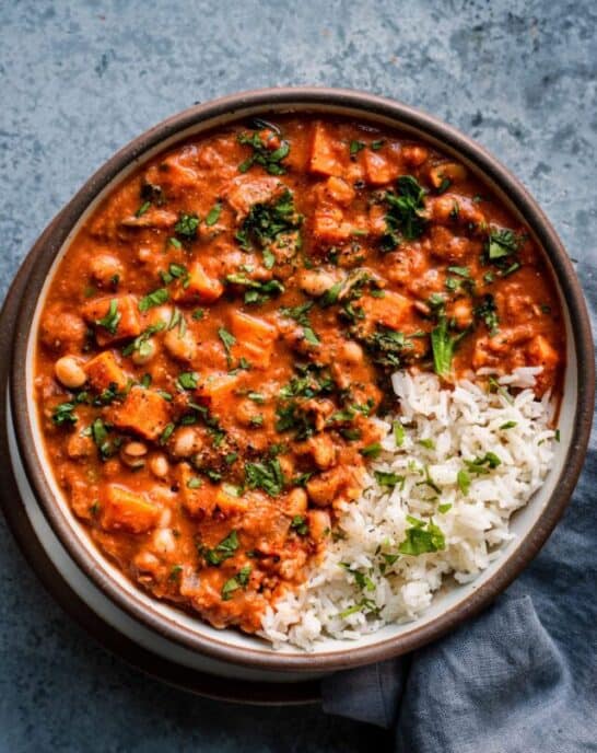 bowl of west african peanut stew garnished with cilantro and side of rice.