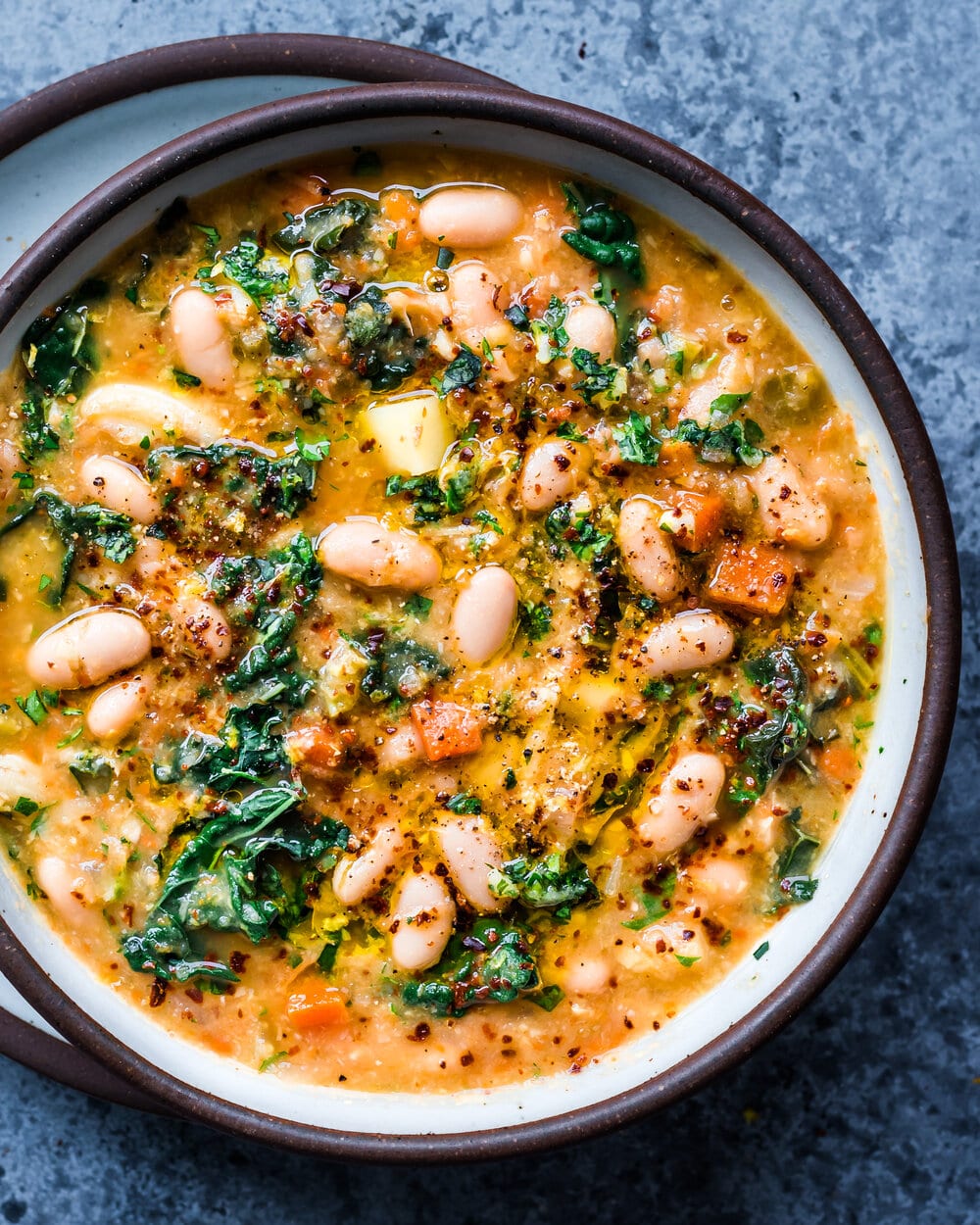 close up of creamy white bean soup with kale and gremolata in bowl