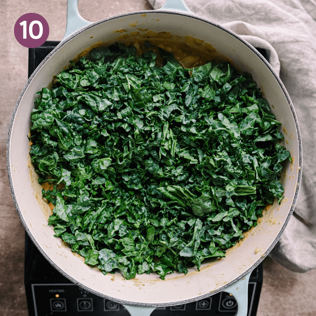 a big bed of chopped tuscan kale sitting on top of a white bean soup in a dutch oven.