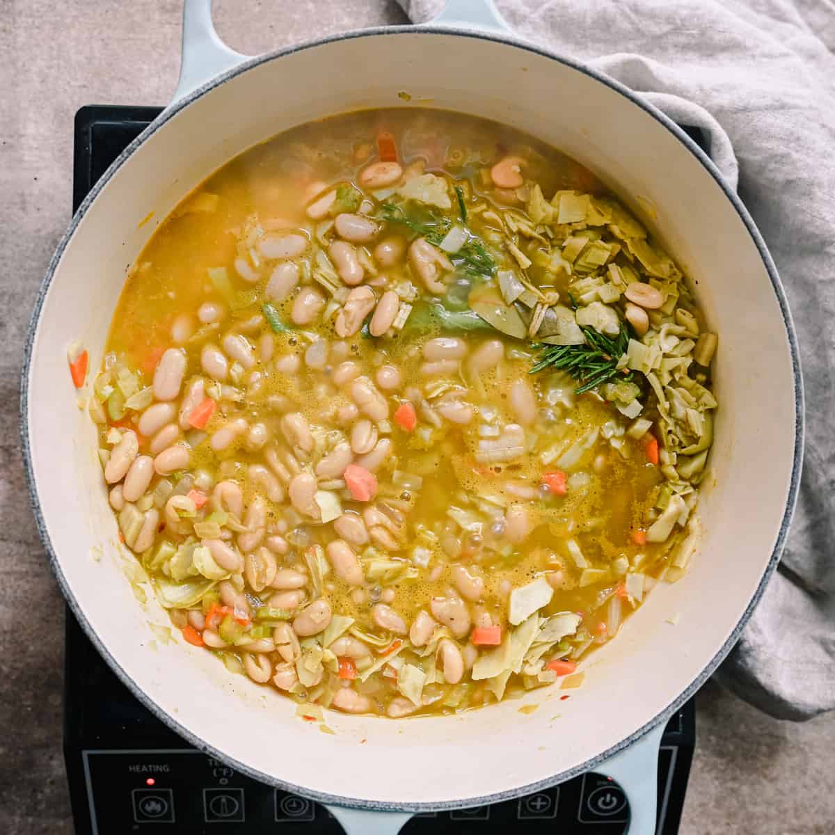 white bean soup simmering in a dutch oven