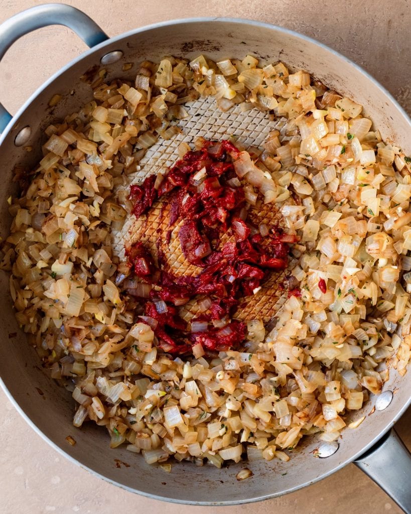 tomato paste added to onions in skillet