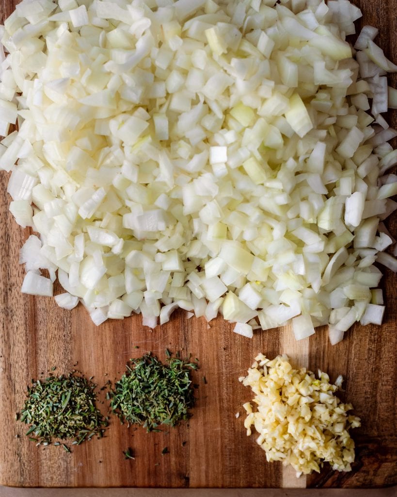 chopped onions, garlic, thyme, and rosemary on cutting board