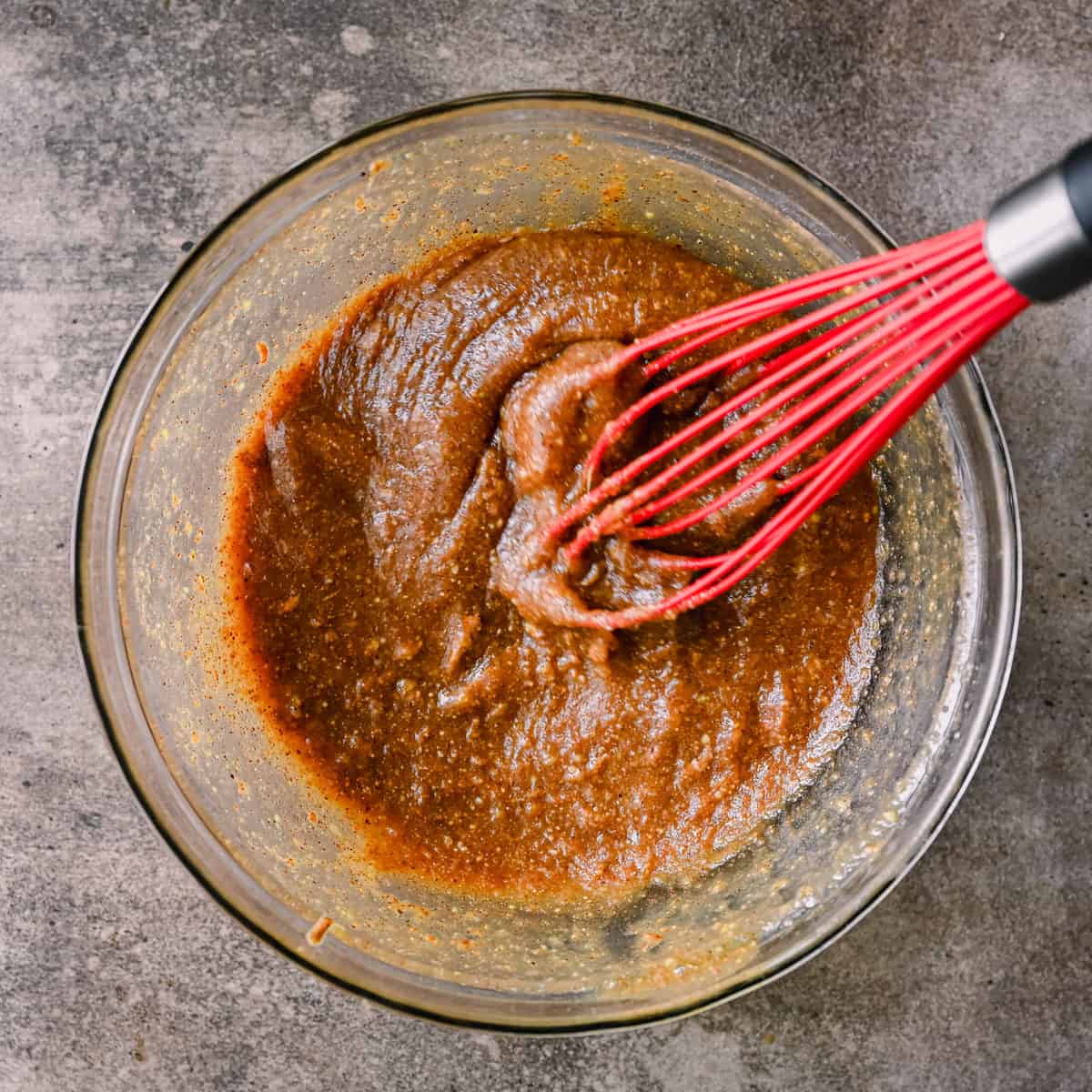 whisking almond butter with maple syrup in a bowl.