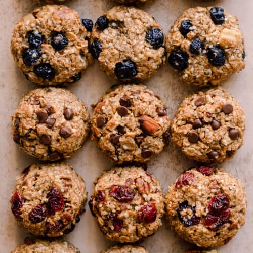 a variety of breakfast cookies with different flavor variations on a light pink surface.