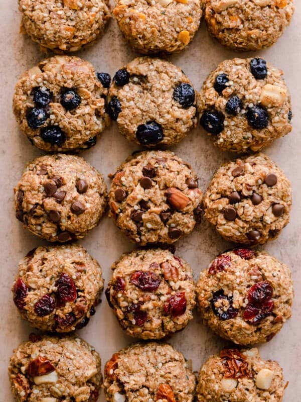 a variety of breakfast cookies with different flavor variations on a light pink surface.