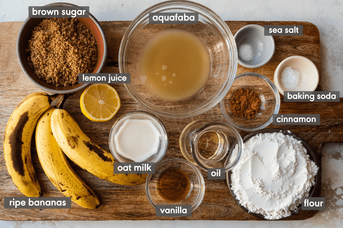 ingredients for vegan banana bread laid out on a wooden cutting board with ingredients labeled.