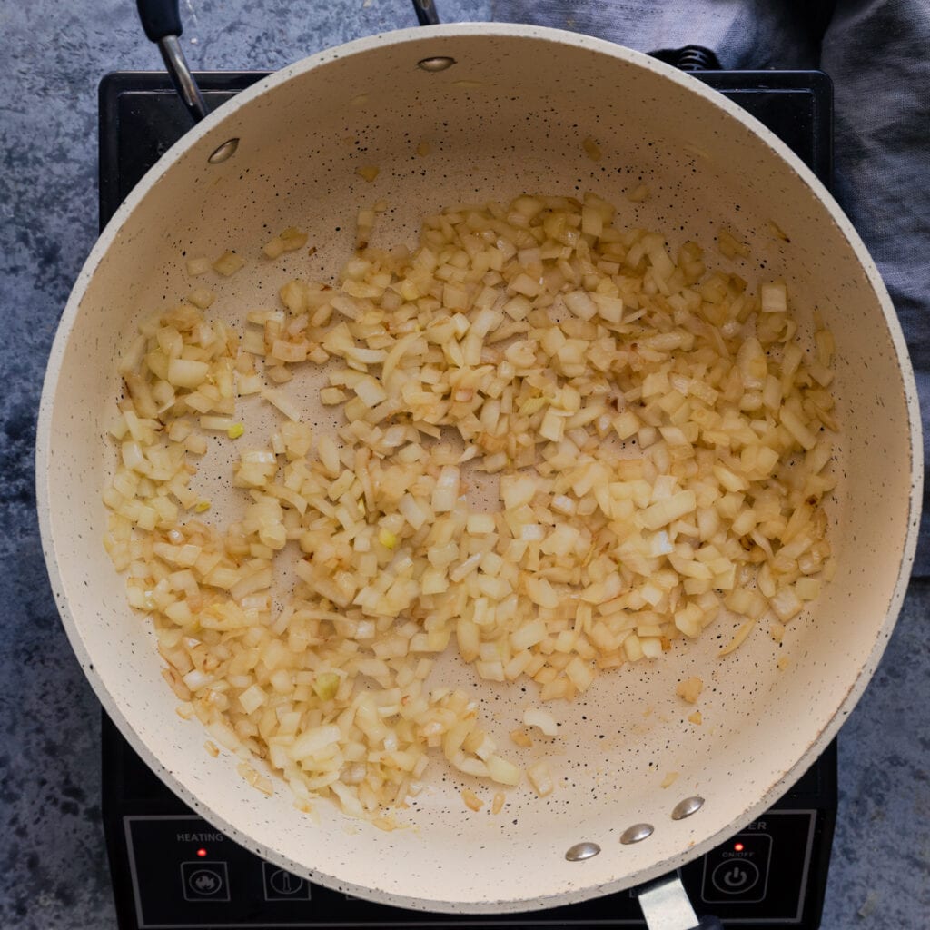 saute pan with diced onions cooking in oil