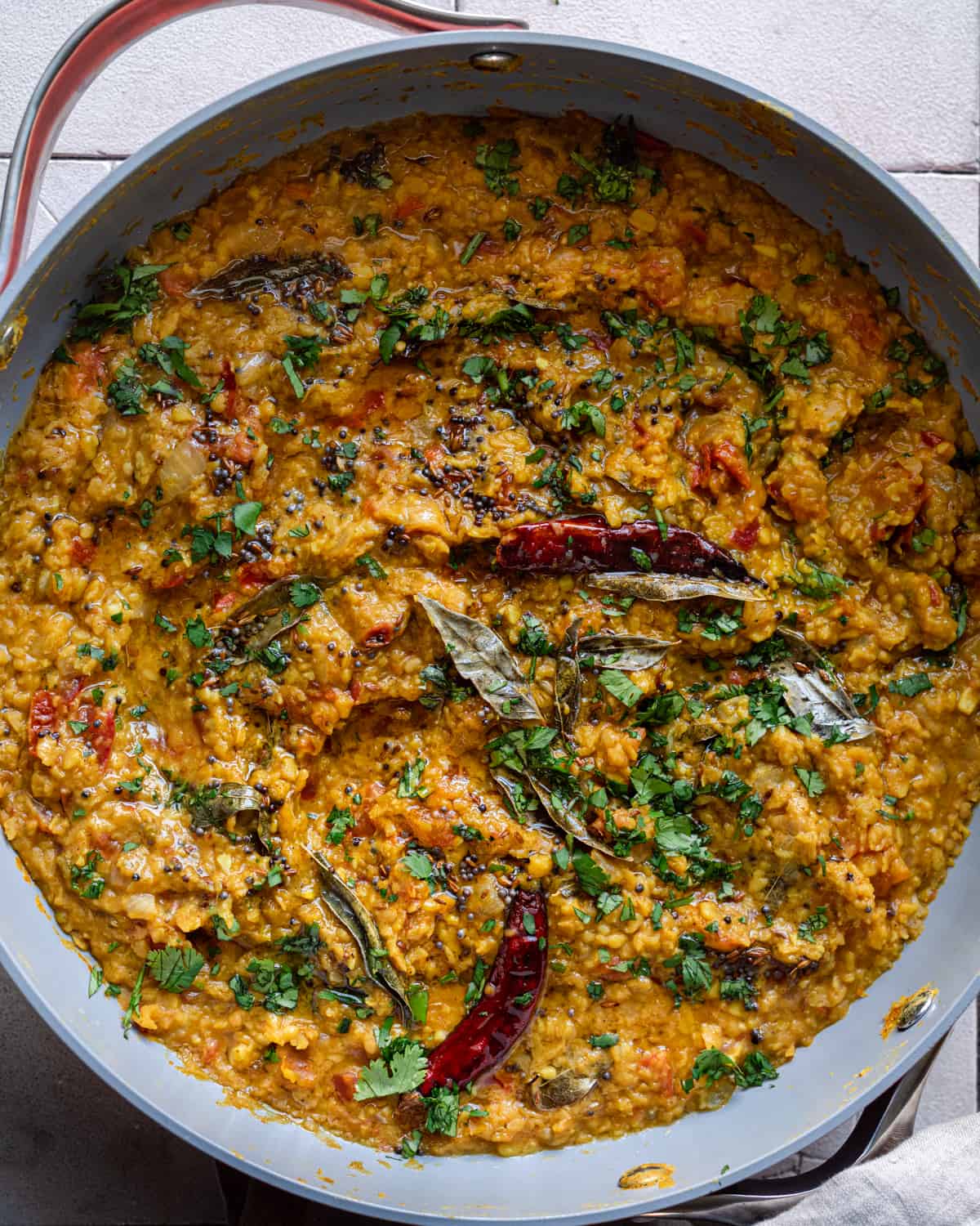 dal tadka in a frying pan, garnished with tadka and cilantro