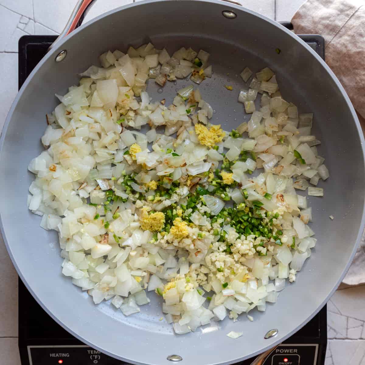 sauteed onions with garlic, ginger and chili pepper in frying pan