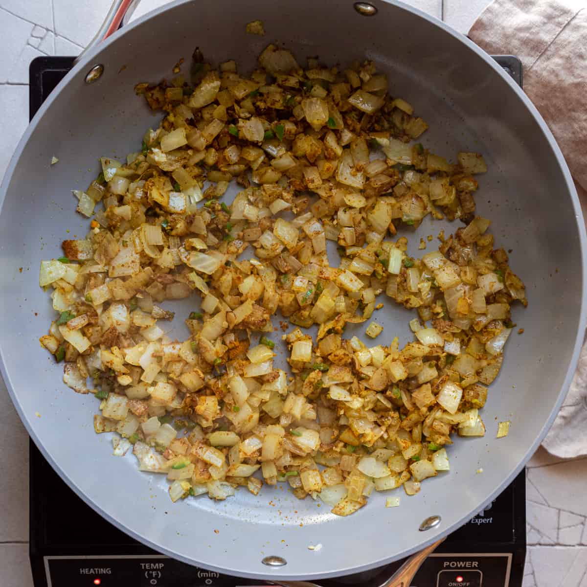 spices stirred into onions in frying pan