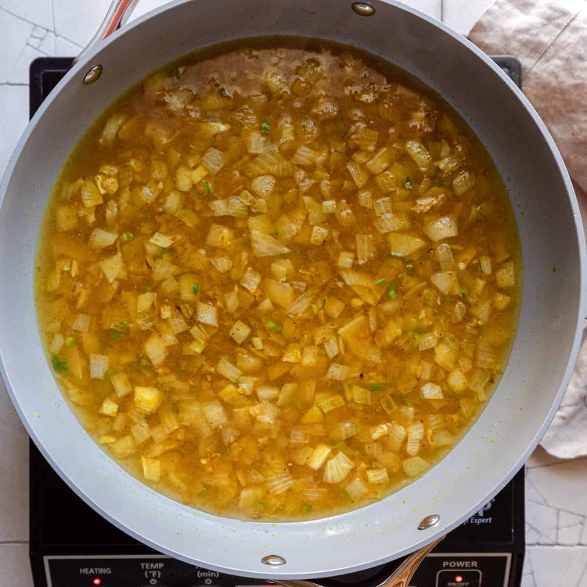 onions and spices with water in frying pan