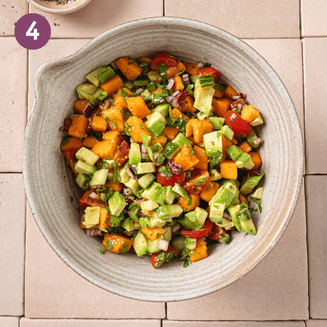large bowl with avocado on top of the mixed mango salsa.