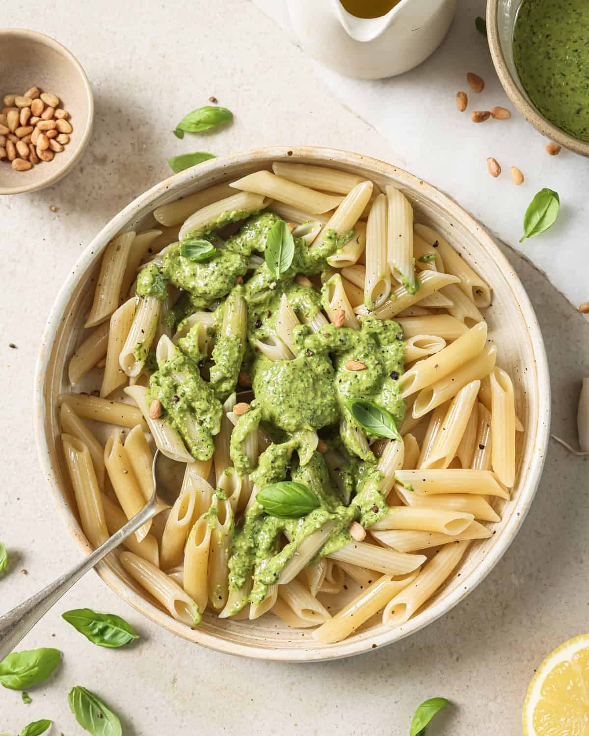 white bowl with penne pasta with vegan pesto dolloped on top.
