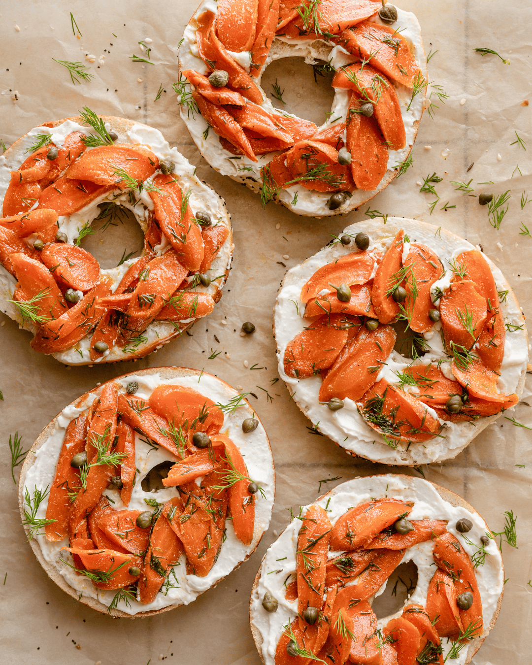 carrot lox on bagels on a piece of parchment paper.
