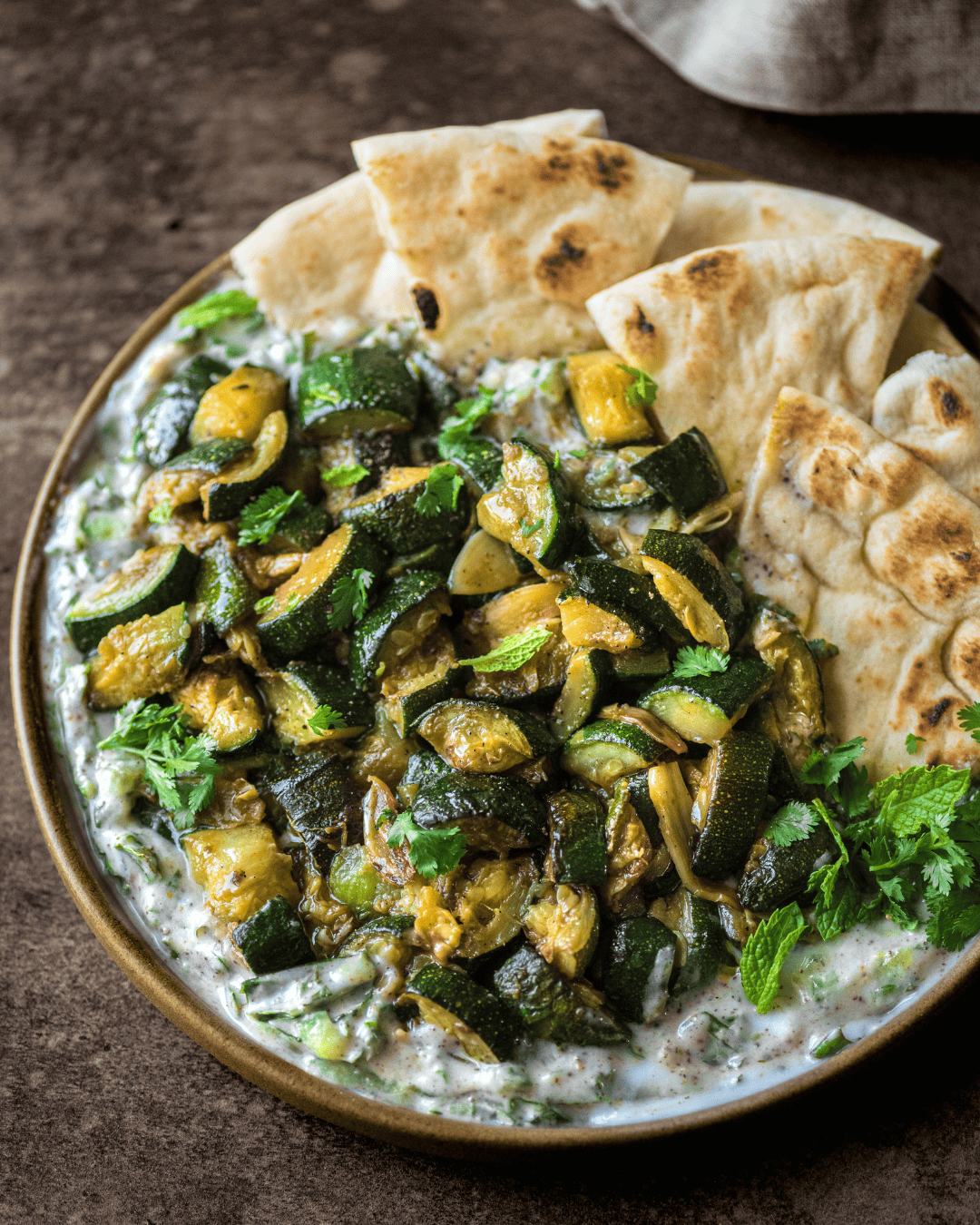 jammy zucchini, yogurt sauce and pita on a plate.