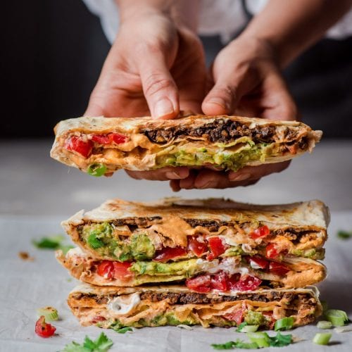 cut in half vegan crunchwrap supreme being held by woman.