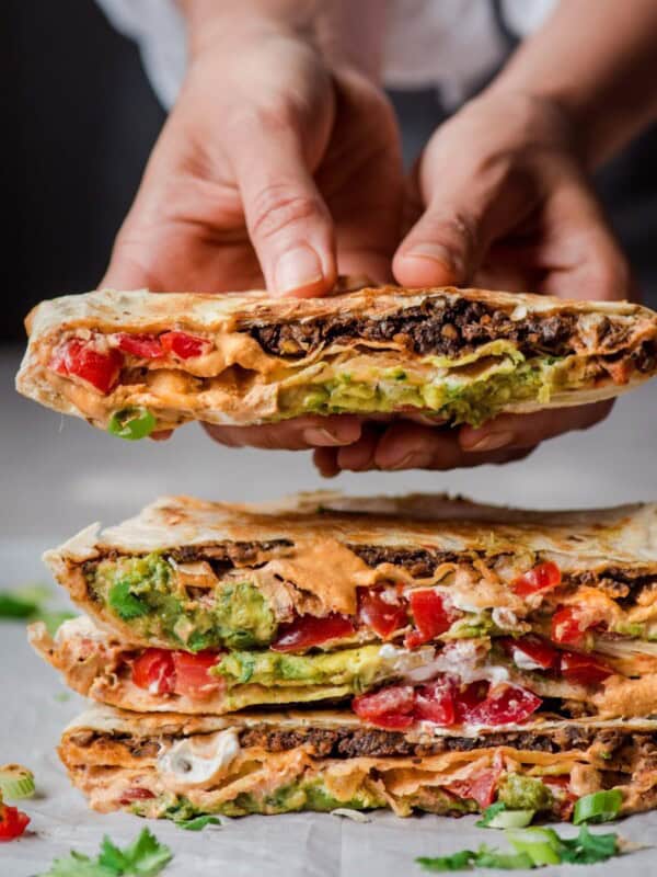cut in half vegan crunchwrap supreme being held by woman.