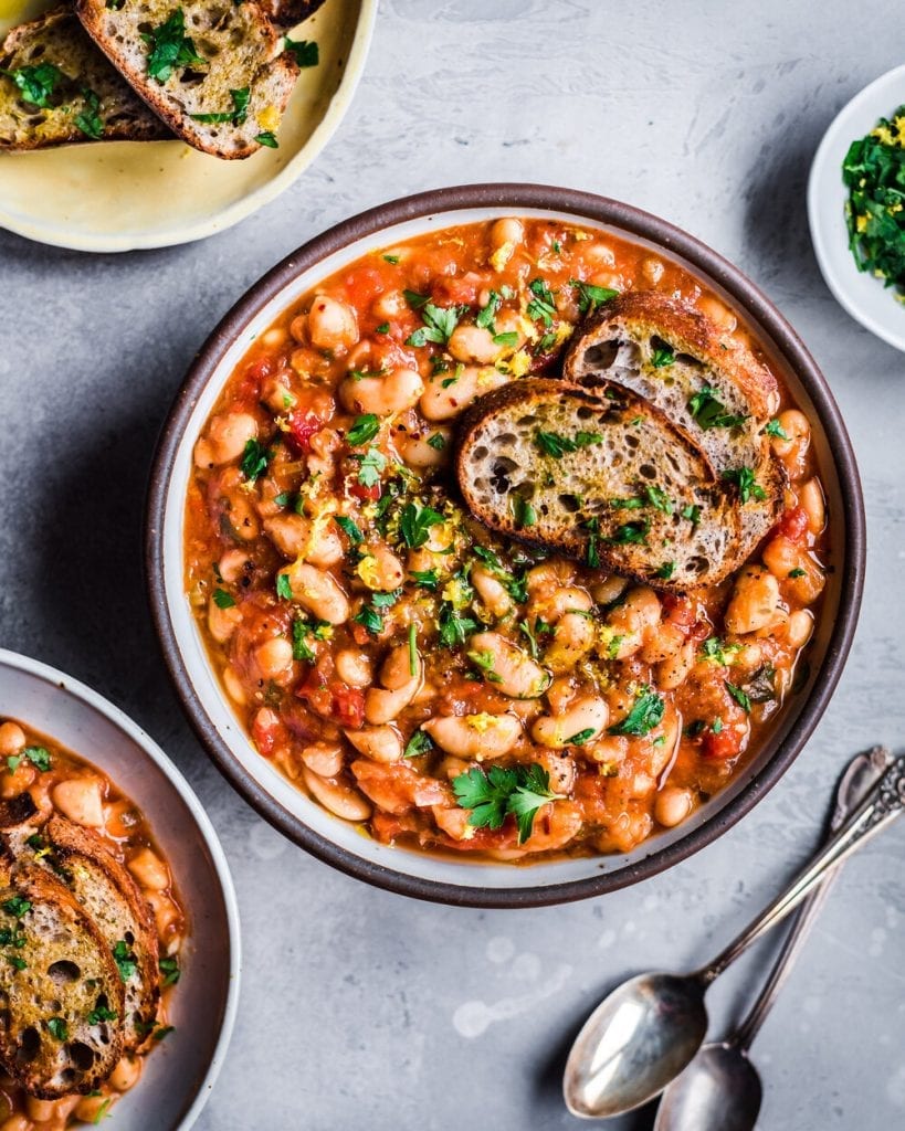 vegan instant pot white bean stew with bread slices and spoons