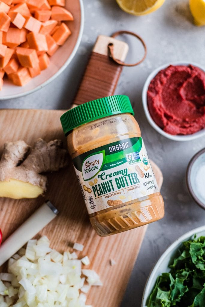 Jar of Aldi Creamy Peanut Butter on cutting board with other ingredients for West African Peanut Stew.