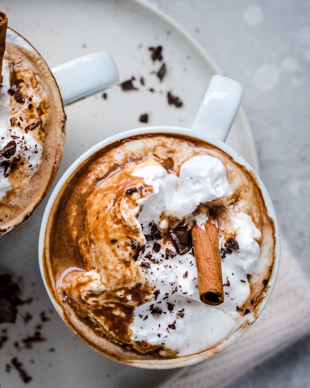 Close up overhead view of hot chocolate in a white mug on a white plate.