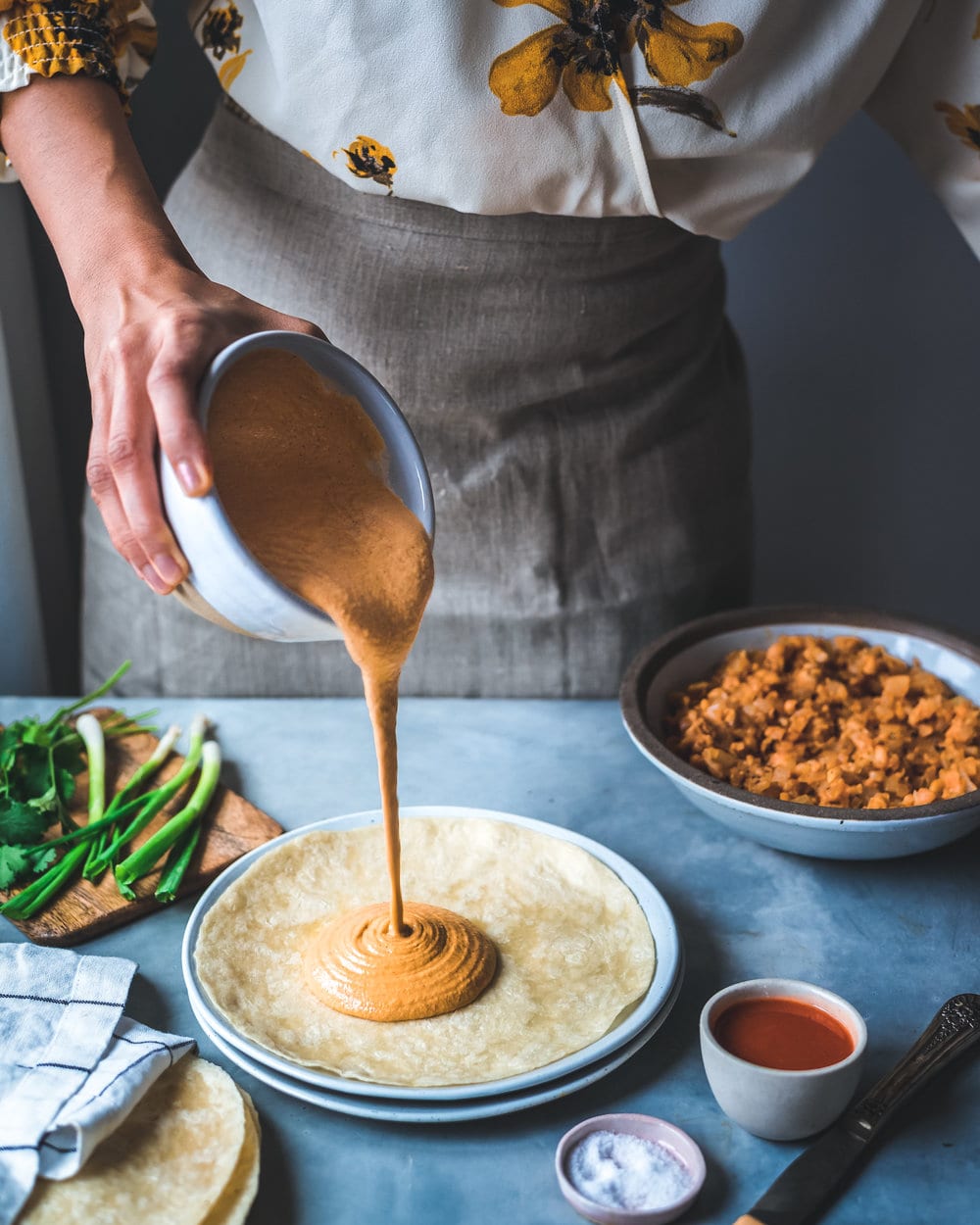 Woman pouring vegan buffalo cheese sauce onto quesadill